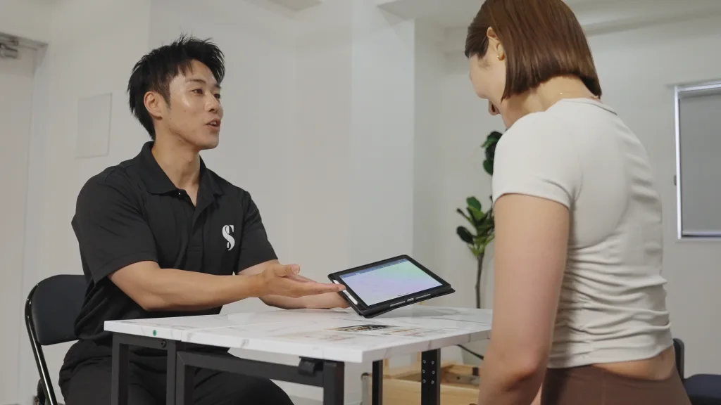 タブレットの画面を見せながらお客様にカウンセリングを行うトレーナー