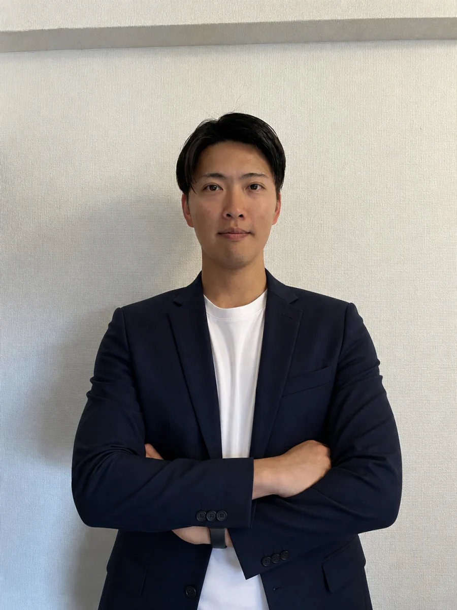 ネイビーのジャケットを着て腕を組む男性スタッフ