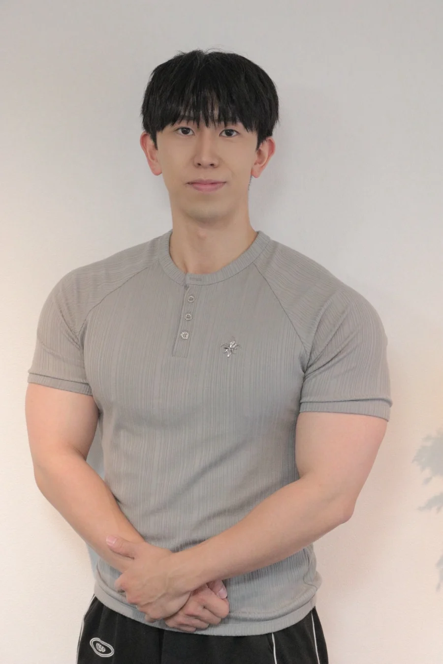 グレーのトップスを着て正面に立つ男性スタッフ