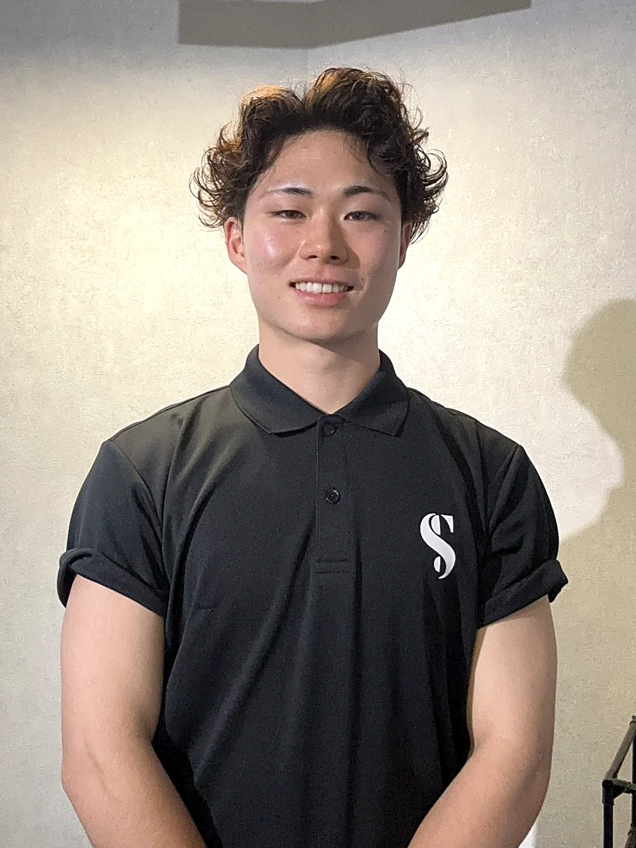 黒いSTLINEポロシャツを着て正面に立つトレーナー