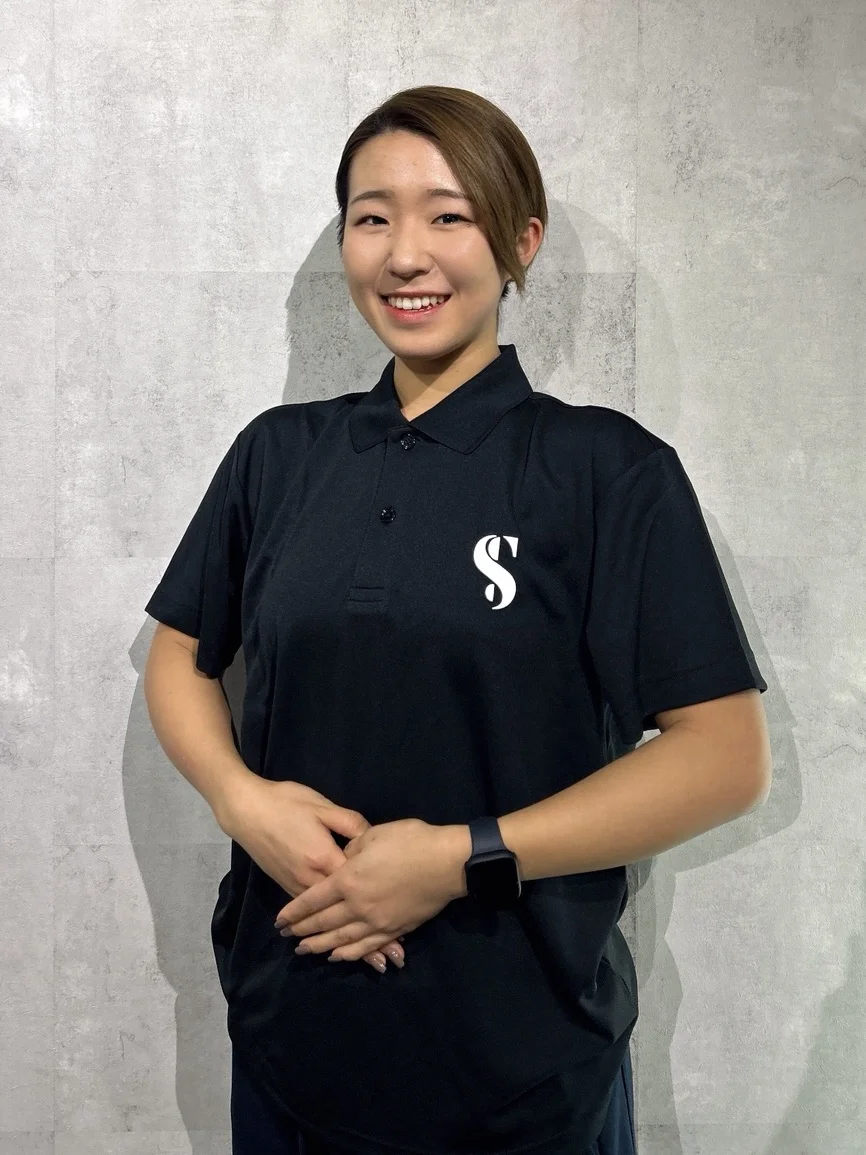 黒いSTLINEポロシャツ姿で微笑む女性トレーナー
