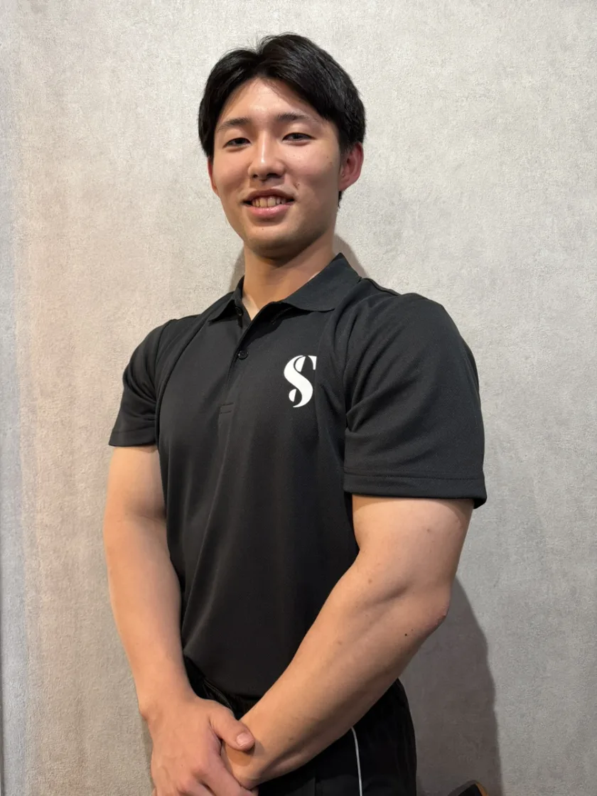 黒いSTLINEポロシャツを着て斜めに立つトレーナー